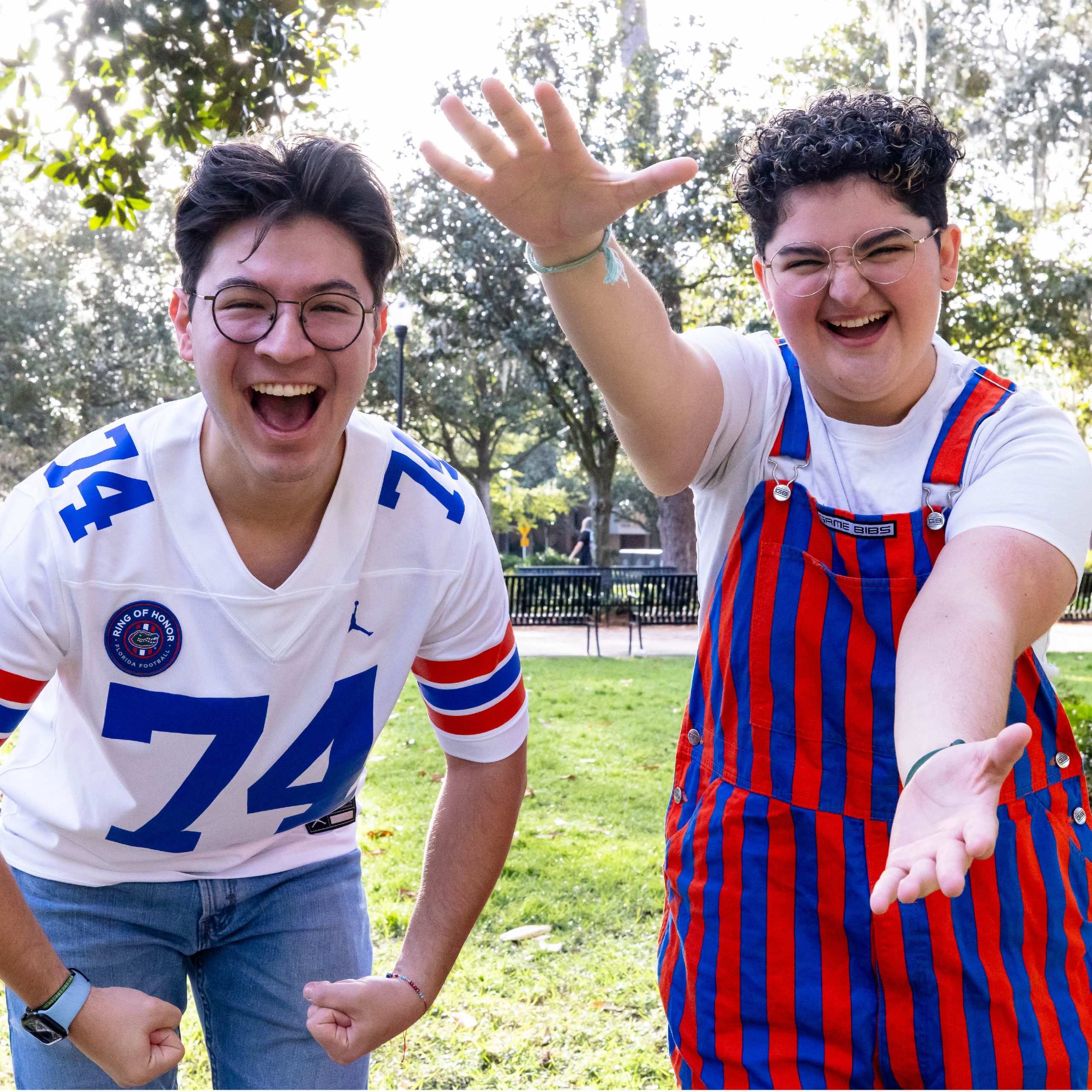 Two students showing their Gator Pride while smiling and doing the Gator Chomp outside.