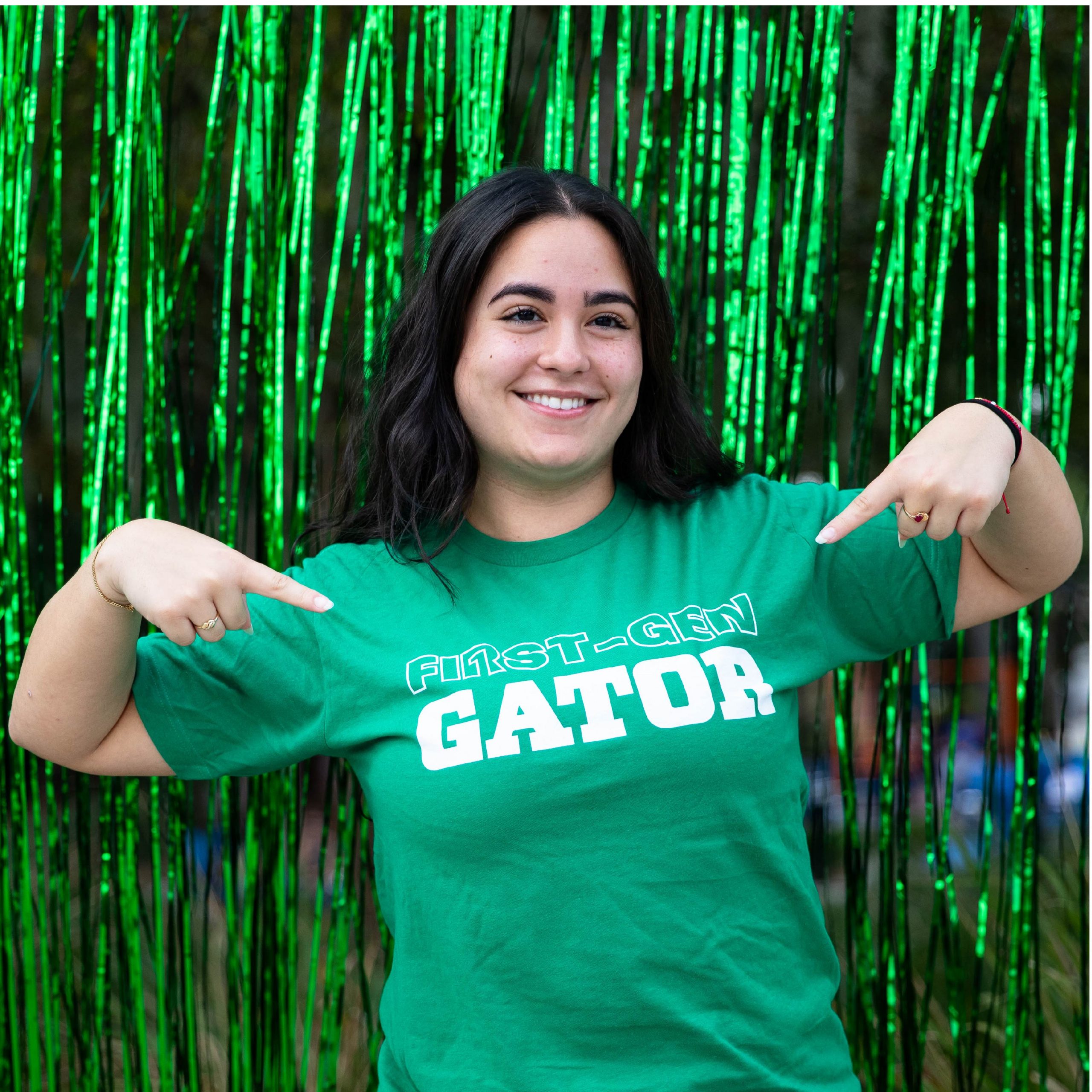 A student pointing to the First-Gen Gator design on their t-shirt.