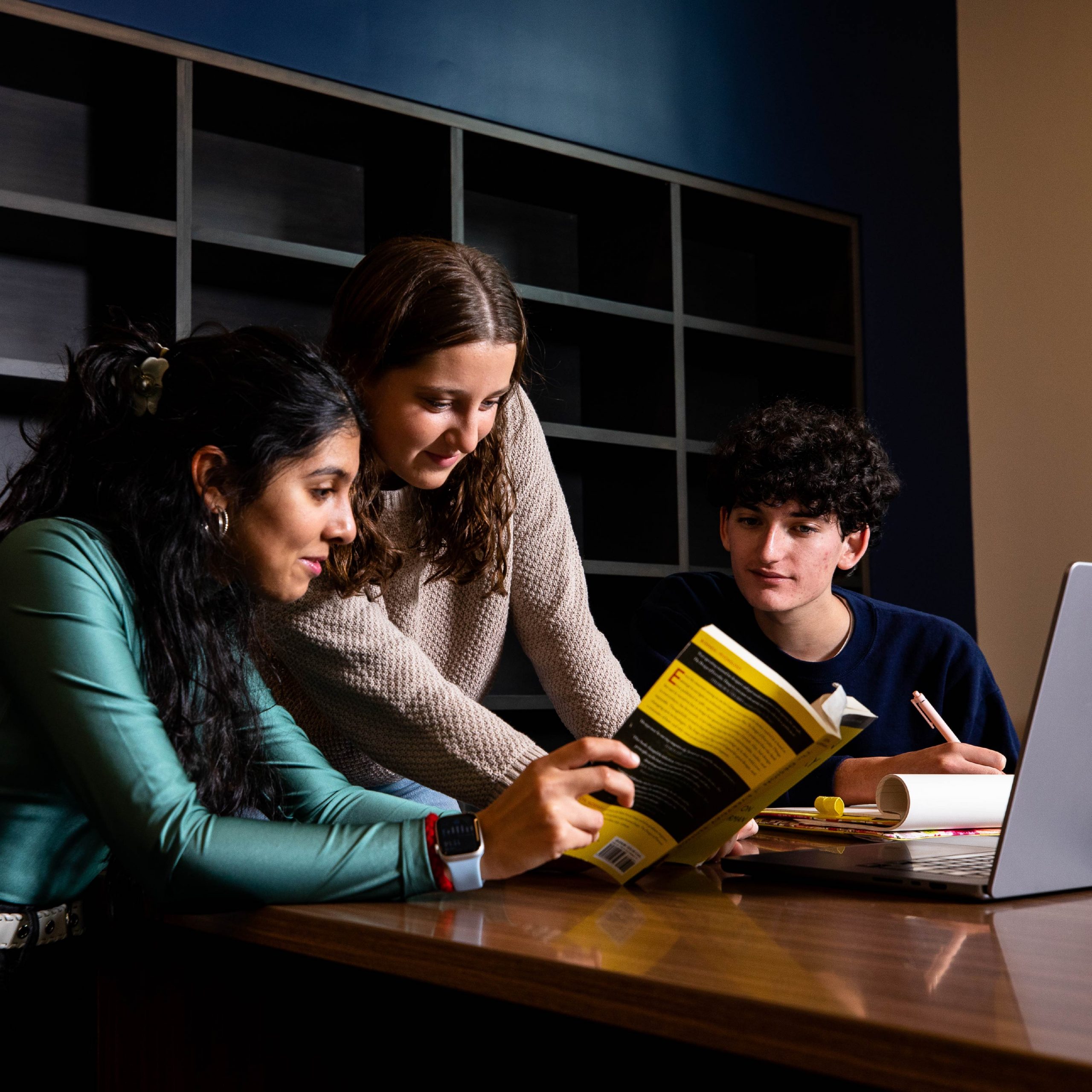 Three students doing research together in a library.