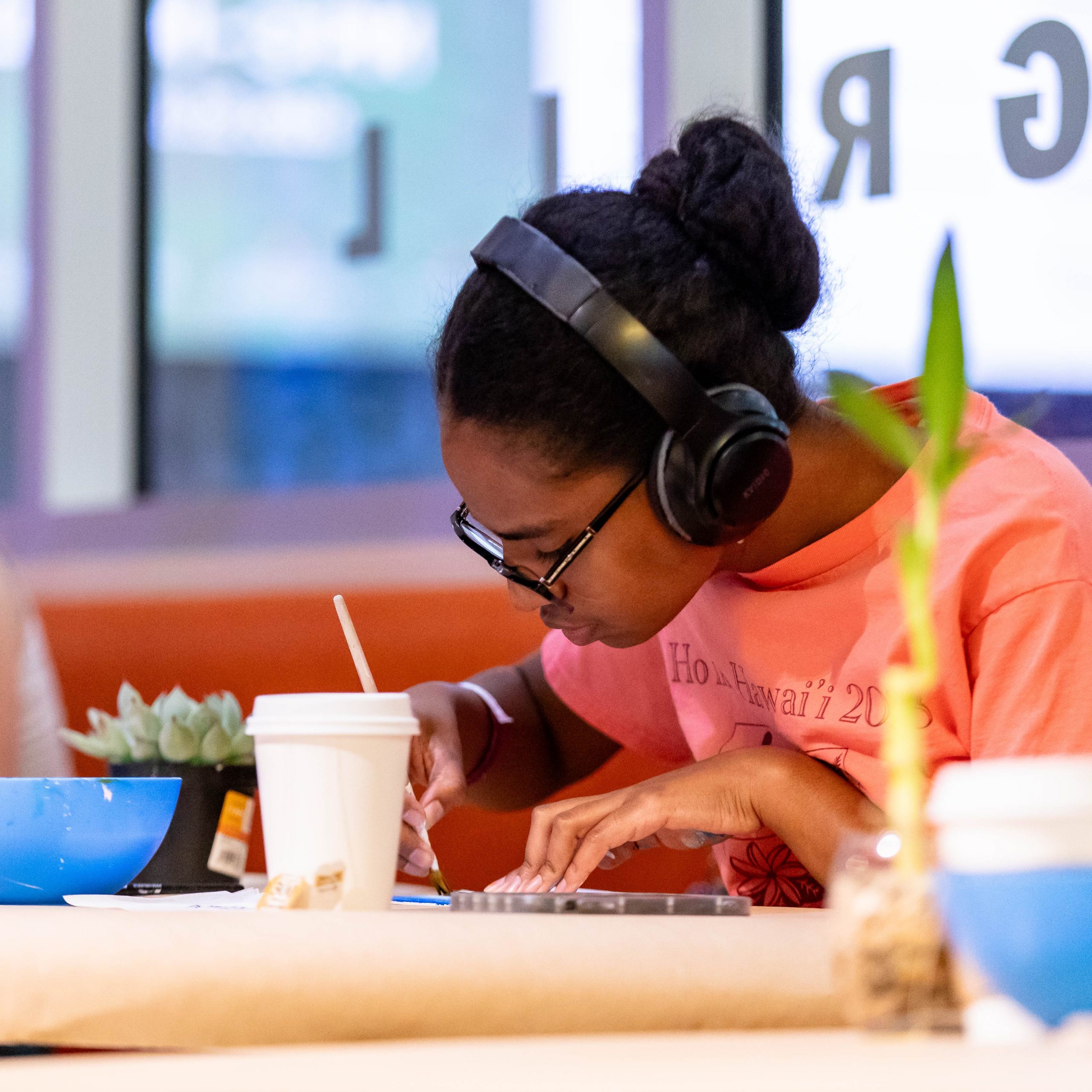 A student with headphones on painting.