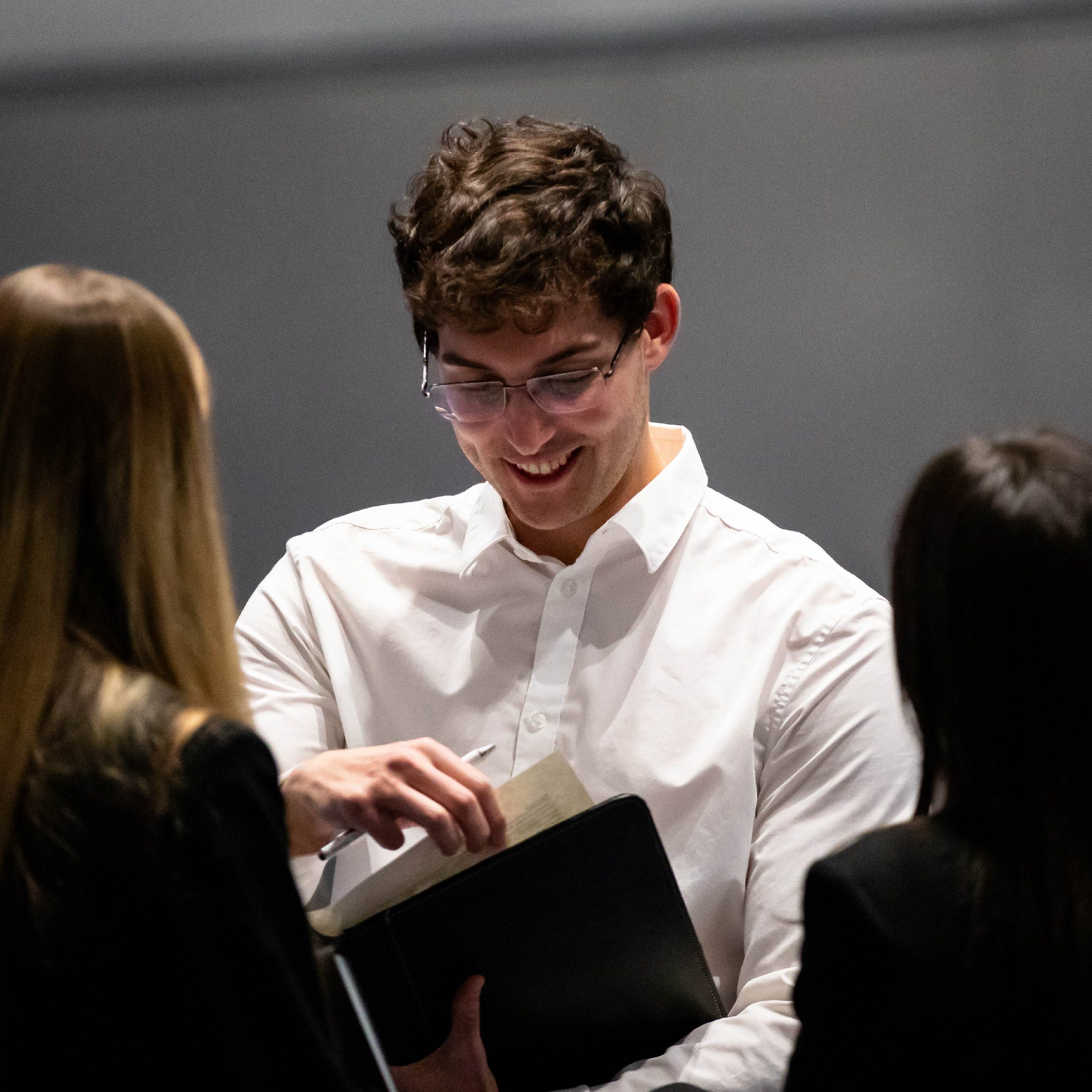 A student in professional wear pulling a document out of a folder.