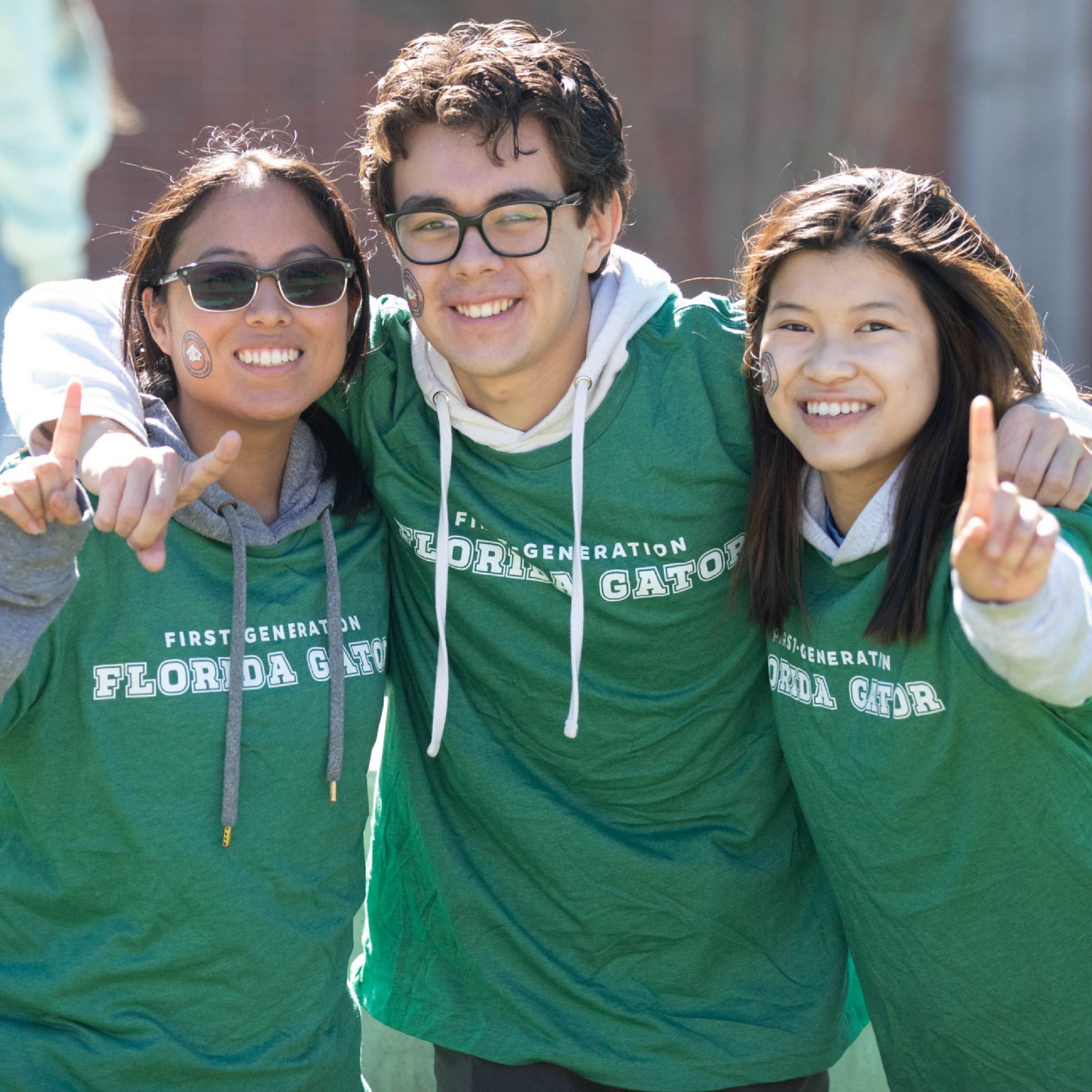 Three students smiling in green First-Gen Florida Gator shirts.